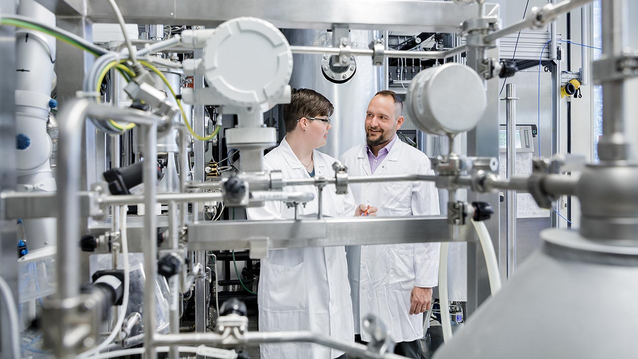 Zwei Forscher stehen zwischen biotechnologischen Versuchsaufbauten.
