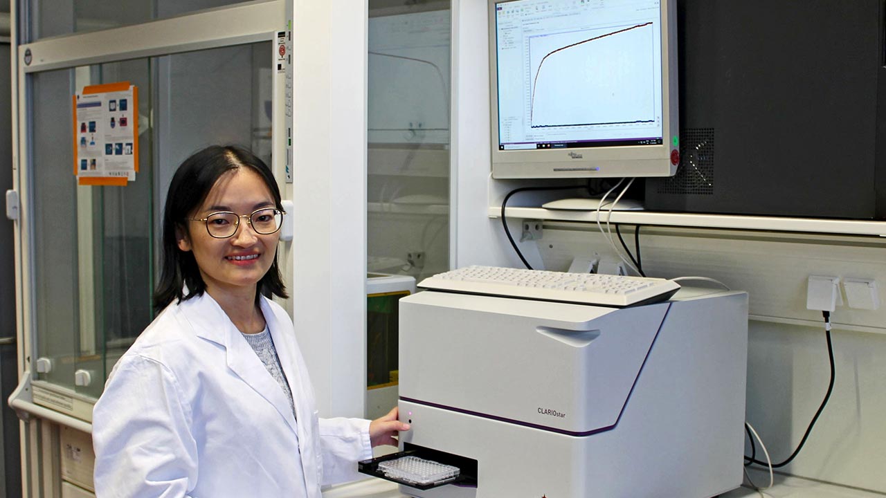Eine Forscherin im Laborkittel vor einem Messgerät