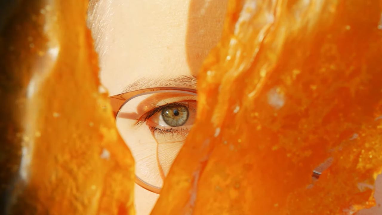 Eine Frau blickt durch eine Lücke in einem orangefarbenen Polymerbauteil